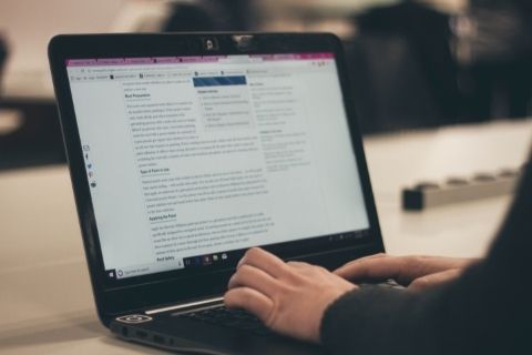 A person typing on their laptop with a CMS open